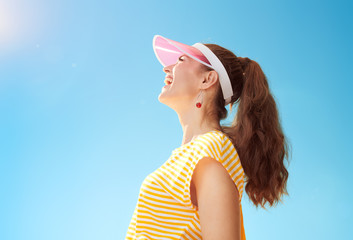 smiling healthy woman against blue sky looking up at copy space