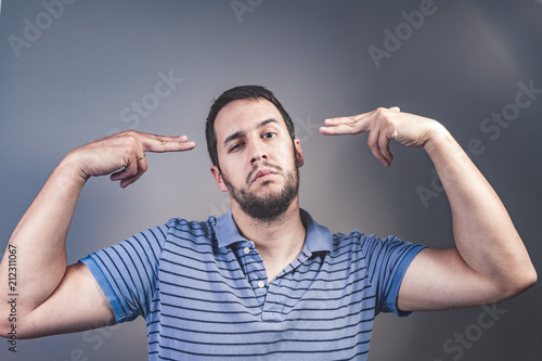 Фото: handsome young man pretending to shoot himself with his hand as a gun handsome young man pretending to shoot himself with his hand as a gun