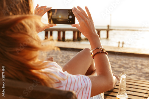 Side view of a young girl in summer clothes taking a picture Side view of a young girl in summer clothes taking a picture