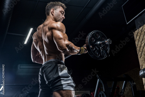 A young brutal male athlete is a bodybuilder with a perfect abs, exercising in the gym. Concept - strength, bodybuilding, styrodes, weightlifting, diet, muscles, sports nutrition, personal trainer © romanolebedev