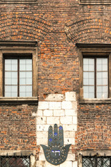 Hamsa on the brick wall of the old building in Jewish Kazimierz district of Krakow, Poland