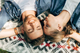 top view of happy young couple with closed eyes lying on patterned cloth