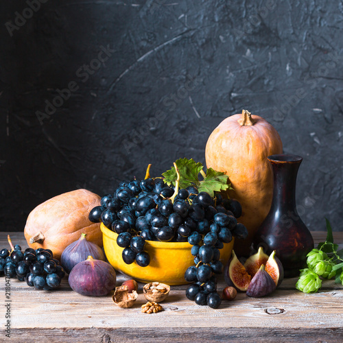 Foto obraz na płótnie canvas jednoczęściowy - Autumn still life in classic style, pumpkin, grapes, figs and walnuts on a dark background