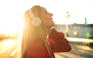 Beautiful girl listening music with headphones while walking in the street