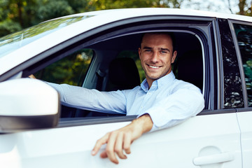Smiling young man sitting in his car