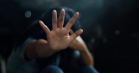 PTSD Mental health concept. Post Traumatic Stress Disorder. The depressed woman sitting alone on the floor and waving refusal to help from people in the dark room background. Film look.