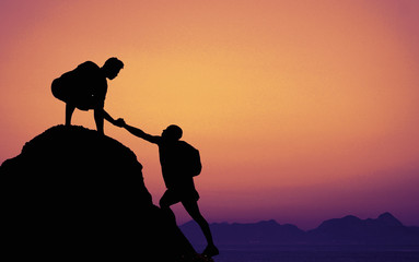 Two climbers on mountain peak on sunset