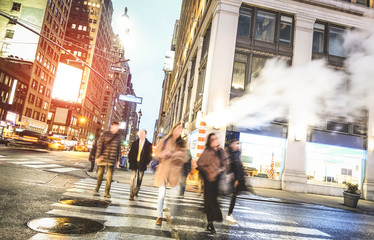 People walking on zebra crossing on West 31th st in Manhattan - Crowded streets of New York City during rush hour in urban business area - Warm desaurated filter with blurred motion on pedestrians