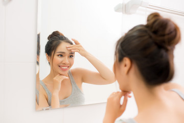 Beautiful woman touching her face by hands in her bathroom