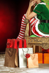 Slim young woman legs and red and white socks. Christamas background and gifts. 