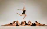 The group of modern ballet dancers dancing on gray studio background