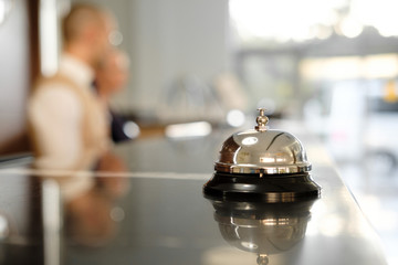 Modern luxury Hotel Reception Counter desk with Bell.  Service Bell locating at reception. Silver Call Bell on table, Receptionists on background. heck in hotel. Concept.