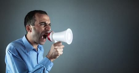 Caucasian businessman screaming into a megaphone.