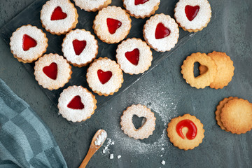 Top view of traditional Christmas Linzer cookies with strawberry jam in wooden tray on dark background