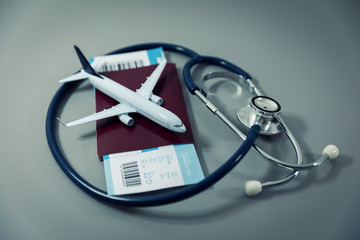 travel insurance - passport with flight ticket and stethoscope on gray background