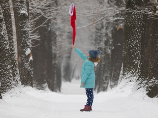 child girl looks at on santa claus hat in the forest