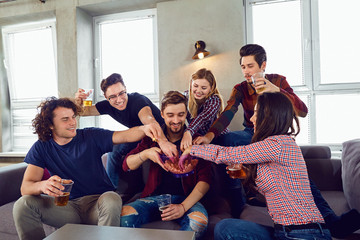 A group of friends with mugs and popcorn at a party indoors