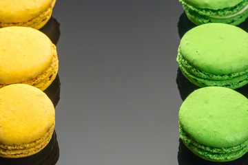 Colorful green yellow French sweet macaroons dessert cake macarons on dark backgrounds copy space
