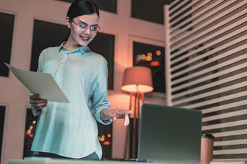 Pleased brunette pointing at computer