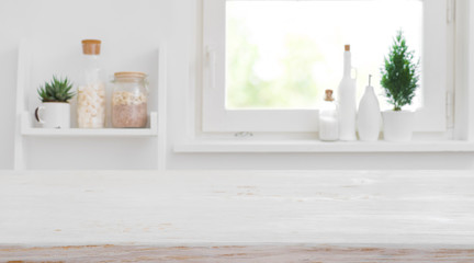 Wooden tabletop in front of blurred kitchen window and shelves