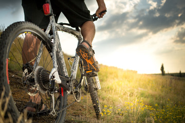 Mountain bike. Low angle view of cyclist riding mountain bike on rocky trail at sunset 