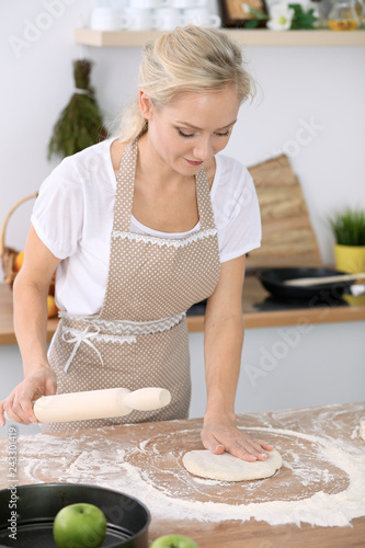 Plakat Mała dziewczynka i jej blondynki mama w beżowych fartuchach bawić się i śmia się podczas gdy ugniatający ciasto w kuchni. Domowe ciasta na chleb, pizzę lub upiecz ciasteczka. Rodzinna zabawa i gotowanie koncepcji