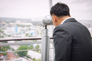 Businessman with binoculars on the top of building searching for golden opportunity concept