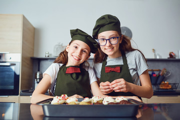 Girls children in cook uniforms in the kitchen.