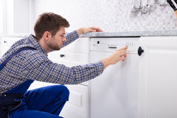 Man Pressing Button Of Dishwasher