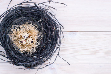 Easter quail eggs in nest and willow branch on white Easter quail eggs in the nest and willow branches on a white wooden background. Space for text.wooden background