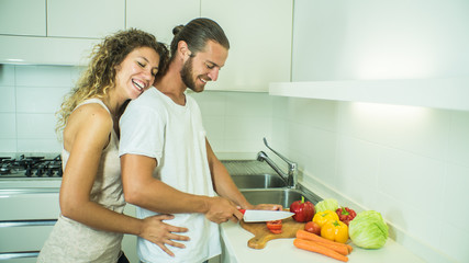 Happy caucasian couple cooking vegetables at home.