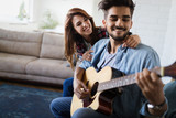 Young handsome man playing guitar for his girlfriend