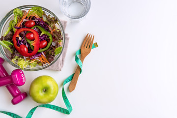 Fresh salad with green apple, dumbbell and measuring tape on white background. Diet, healthy eating concept