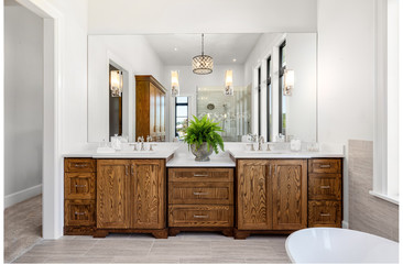 Beautiful bathroom in new luxury home, with double vanity, bathtub, and shower visible in mirror reflection.
