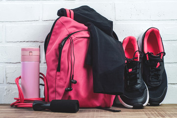 Pink backpack with sportswear, sneakers and a jump rope. The concept of fitness or running