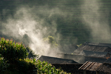Rooftops and smoke in rice terraces landscape China