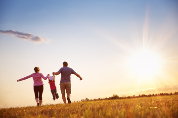 girl with mother and father holding hands on the nature