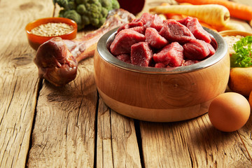Pet food in a wooden bowl with fresh meat
