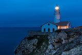 Leuchtturm auf einem Felsen umringt vom Meer, zur blauen Stunde
