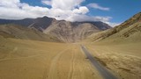Wide aerial shot in the Himalayan mountains, light traffic on an asphalt road