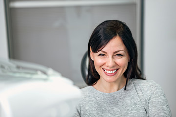 Portrait of a cheerful young woman with beautiful smile in dentist office.