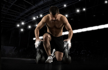 Muscular man workout with kettlebell at gym