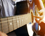 Close-up hand playing acoustic guitar and sitting in indoor.