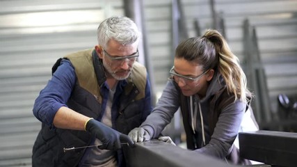 Metalworker with apprentice in workshop