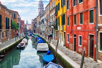 Old narrow water canal with boats in Venice, Italy. Street with colorful architecture of Venice. 