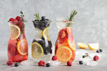 Berry infused water, coctail, lemonade or tea. Summer iced cold drinks with strawberry, blueberry, raspberry, lemon and herbs Selective focus