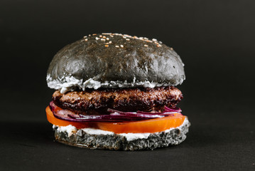 Tasty burger with black bun on a black background
