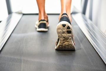 Male muscular feet in sneakers running on the treadmill at the gym.