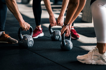 Group people in sportswear holding dumbbells during workout at the gym, low angle, close-up.