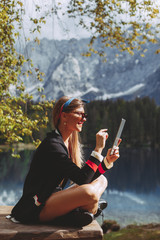 Young woman on the lake using digital tablet